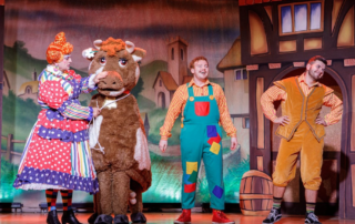 3 actors on stage with a cow